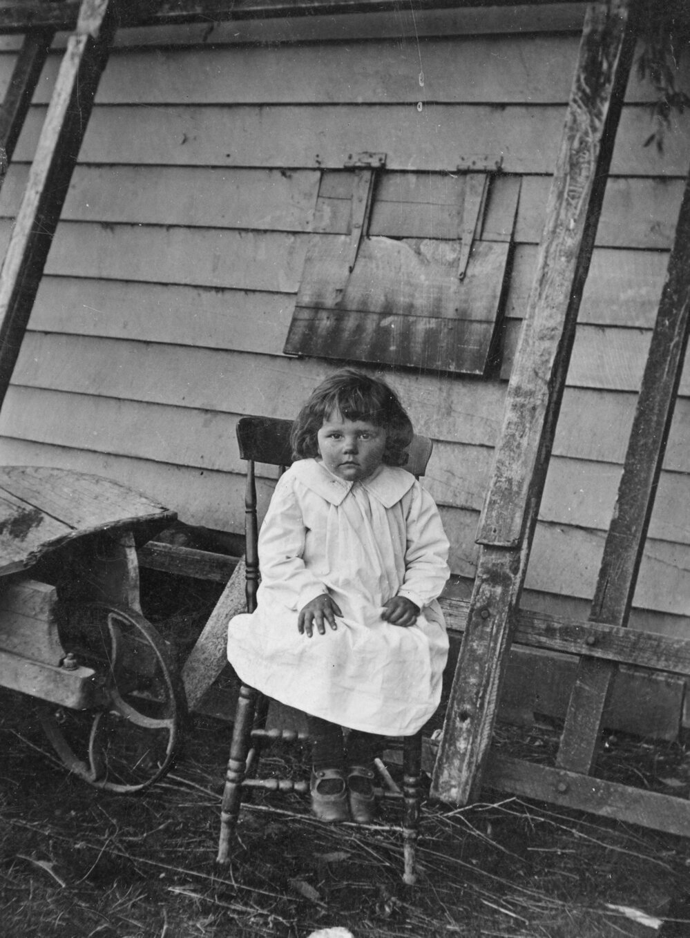 Seated Girl in Front of Farm Building