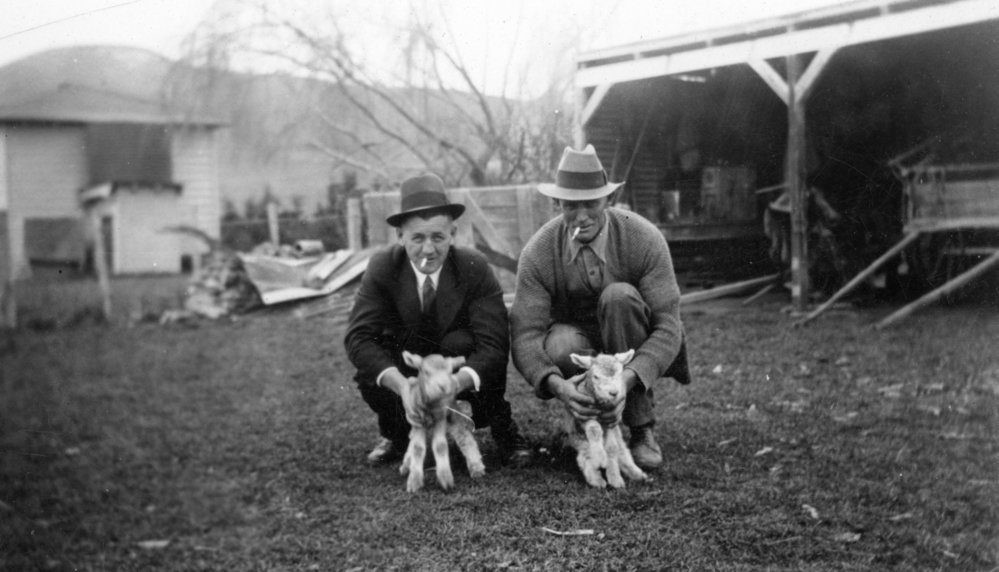 Two Men Holding Lambs