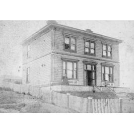Woman on Verandah of Large Wooden House