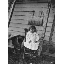 Seated Girl in Front of Farm Building