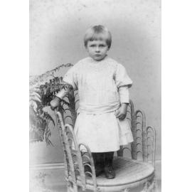 Studio Portrait of Child Standing on Wicker Chair