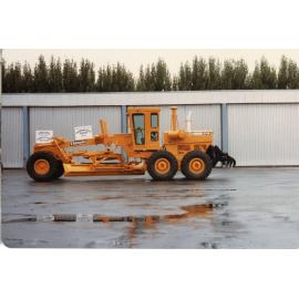 Champion Road Grader Beside Sheds